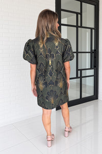 Woman wearing Entro green dress with puff sleeves and nude heels Back