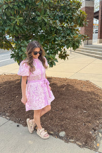 Woman wearing Sunday Mornings pink eyelet button front dress by TCEC with adjustable waist tie
